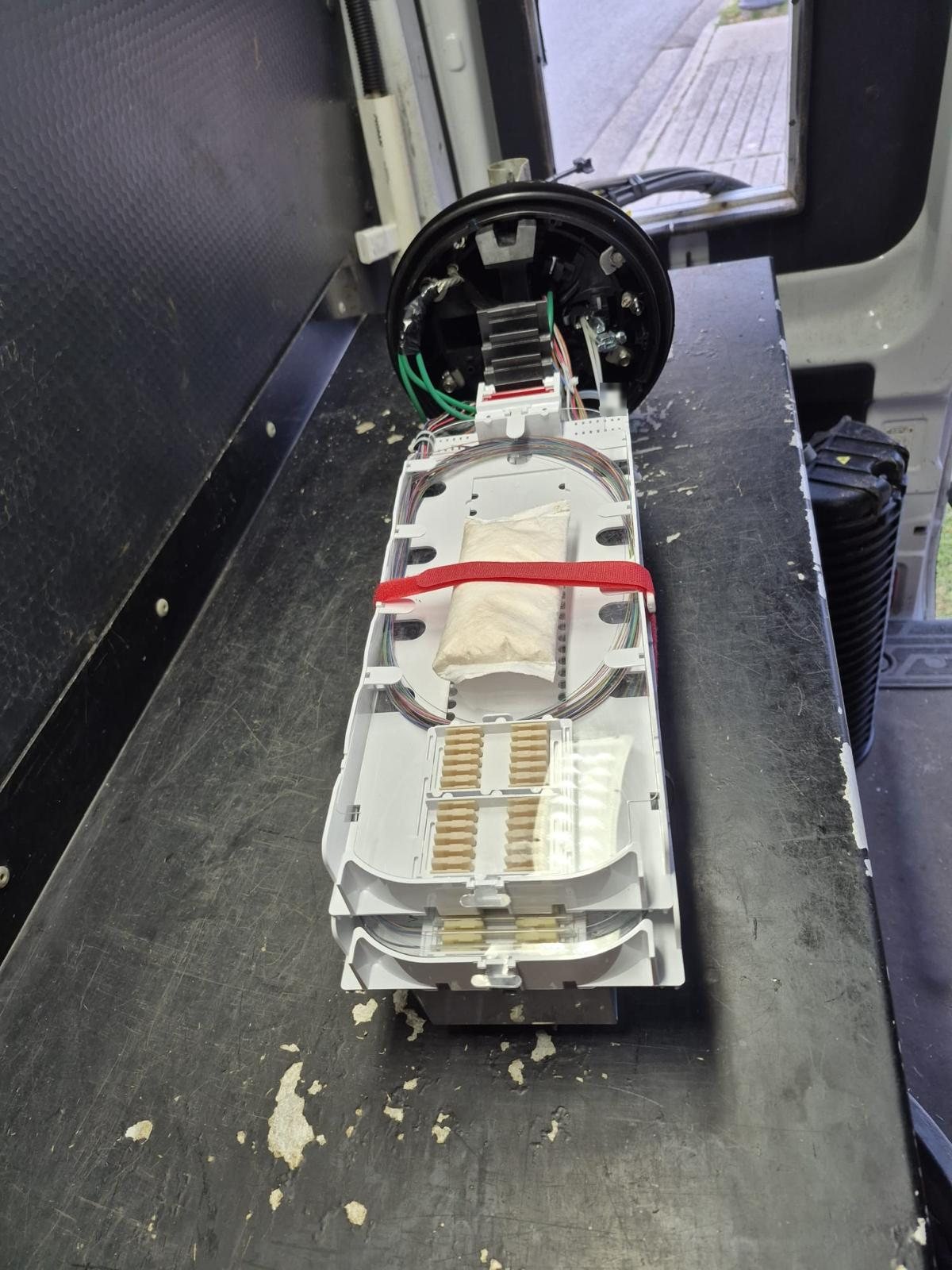 Opened fiber splice closure with stacked splice trays and managed fiber loops on a work surface