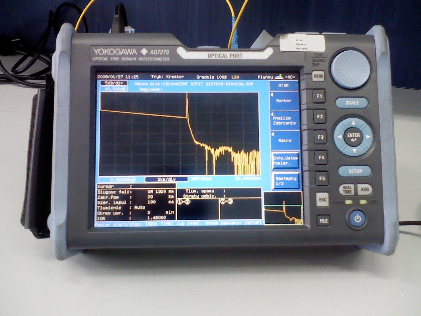 Illustrative OTDR instrument on a calibration stand with a trace displayed on its screen